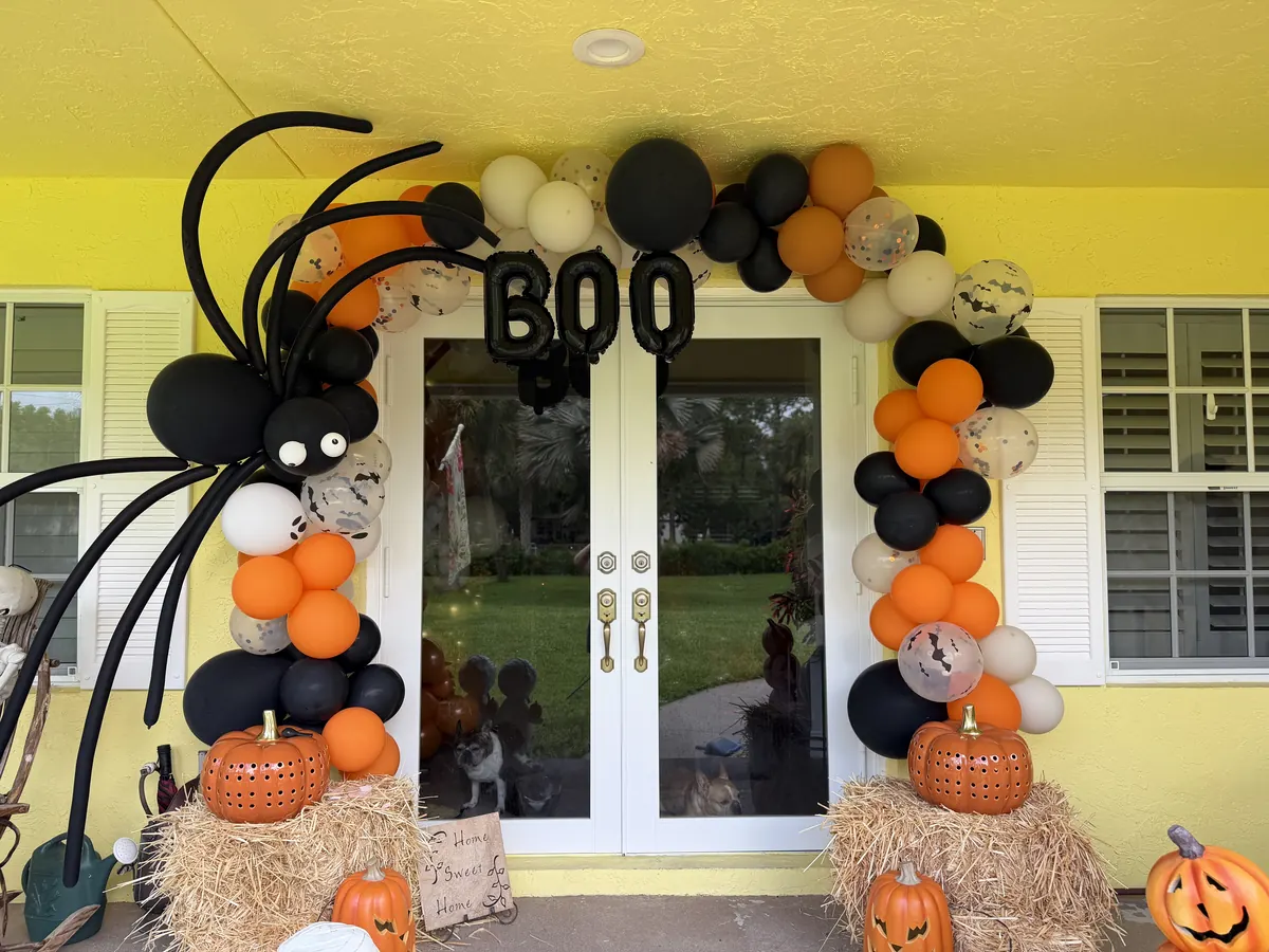 Black, orange and white Halloween garland around a front door with BOO letters