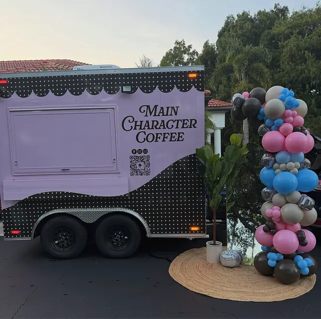 Pink, blue and disco balloon column beside a lavender coffee trailer