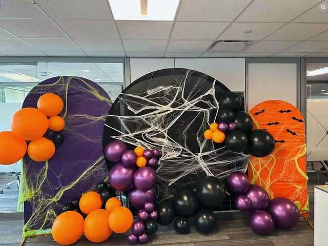 Three Halloween arches in an office with black, orange and purple balloons